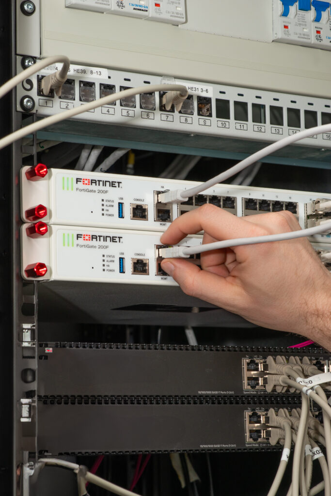 Techniker konfiguriert FortiGate Firewall im Serverschrank für IT-Security
