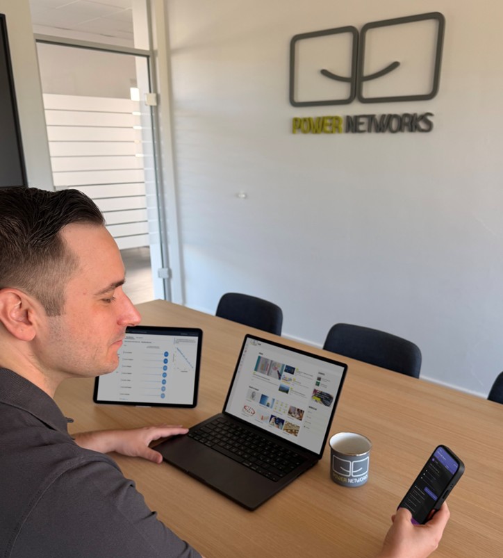 Power Networks Mitarbeiter arbeitet mit Laptop und Tablet an digitaler Zusammenarbeit mit Microsoft 365